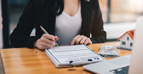 Midsection of woman reading book on table