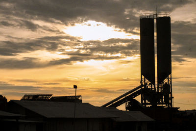 Low angle view of silhouette factory against sky during sunset