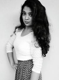 Portrait of young woman standing against white background