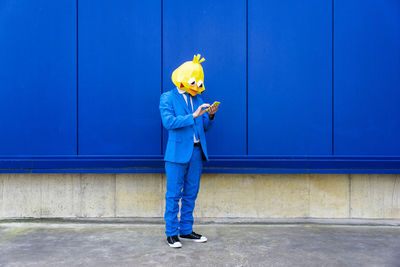 Side view of man holding umbrella against blue wall