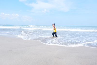 Full length of man standing on beach against sky