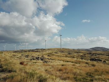 Wind turbines on field against sky