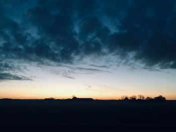 Silhouette landscape against dramatic sky during sunset