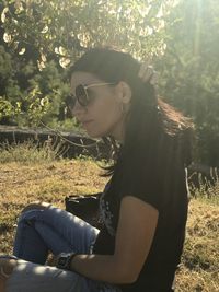 Side view of young woman sitting on field