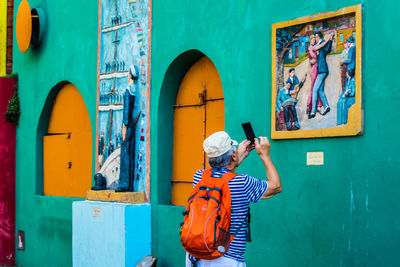 Rear view of woman standing against graffiti wall