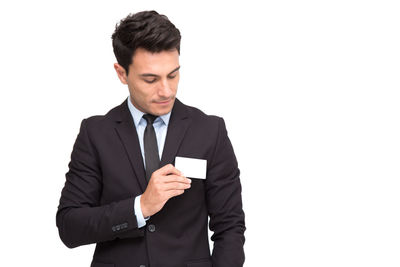 Young man looking away while standing against white background