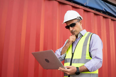 Man wearing hat standing against wall