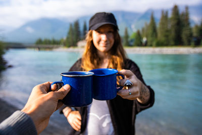 Portrait of young woman holding ice cream in lake