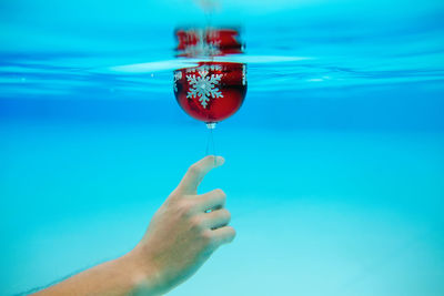 Close-up of hand holding christmas decoration in blue water