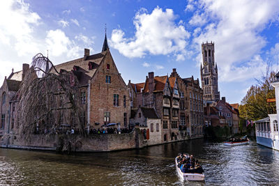 Buildings by river against sky in city