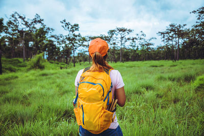 Rear view of woman with backpack standing on grassy land
