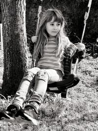 Portrait of girl sitting on tree trunk