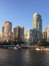 Modern buildings by river against sky in city