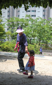 Side view of grandmother and granddaughter walking on footpath at park