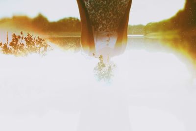 Multiple exposure of upside down woman with trees against sky