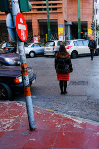 Rear view of woman with umbrella on road in city