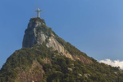 Low angle view of christ the redeemer on mountain against blue sky