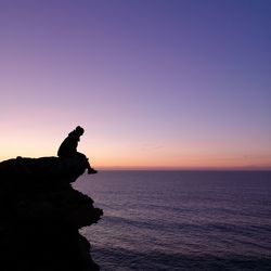 Silhouette rock on sea against sky during sunset