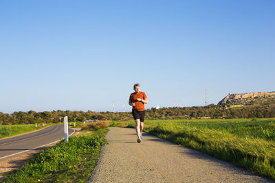 Man running on road against clear sky