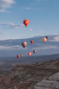 Hot air balloons flying over rocks against sky