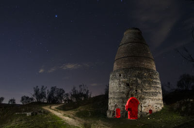Rear view of men on field against sky at night