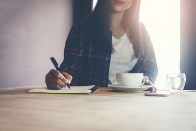 Midsection of woman holding ice cream on table