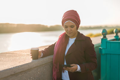 Portrait of young woman standing against sea