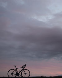 Silhouette of bicycle against cloudy sky
