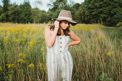 Girl wearing a hat standing in a field of goldenrod