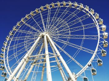 Low angle view of ferris wheel against blue sky