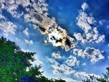 Low angle view of trees against cloudy sky