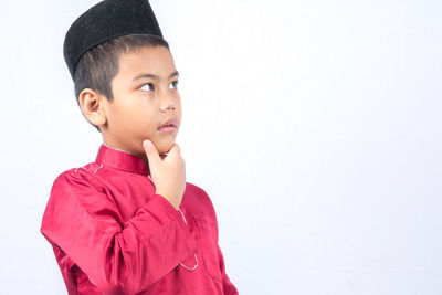 Cute boy wearing maroon traditional clothing standing against white background