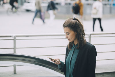 Confident businesswoman using smart phone in city