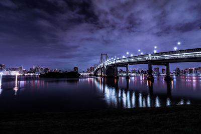 Illuminated bridge over river against sky at night