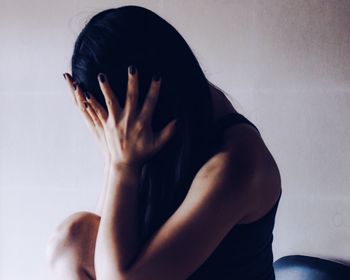 Close-up of woman covering face with hands at home