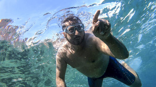 Full length of shirtless man swimming in sea