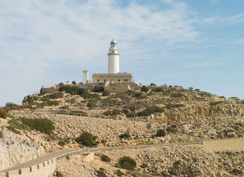 Low angle view of lighthouse on coastline against sky during sunny day