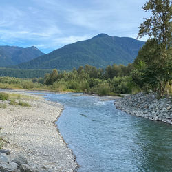 Scenic view of river by mountains against sky