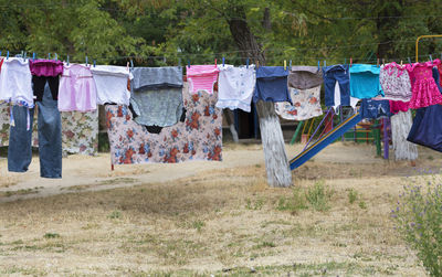Clothes drying on clothesline on field against trees