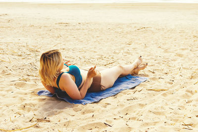 Young girl sunbathing on a wild beach by the sea