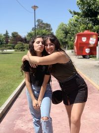 Portrait of smiling female friends standing on footpath