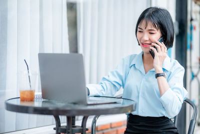 Young woman using mobile phone while sitting at office