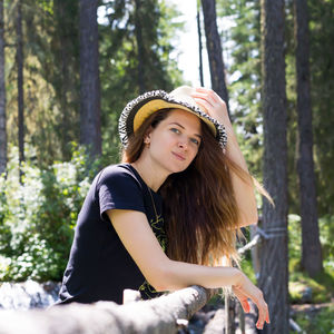 A young beautiful tourist walks along boards through a stormy mountain stream