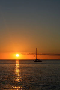 Silhouette sailboat in sea against romantic sky at sunset