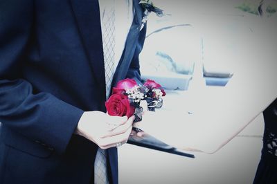 Midsection of man in suit holding roses