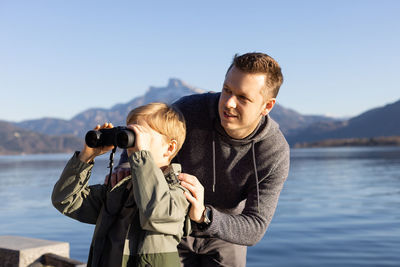 Father assisting boy looking through binocular