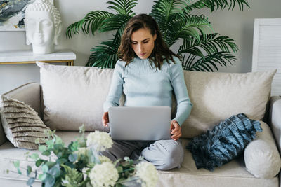 Beautiful woman on the couch working on a laptop.