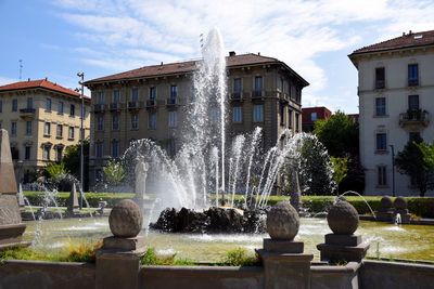 Fountain in city against sky