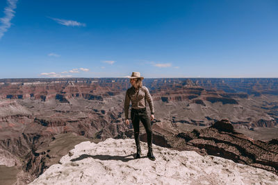 Man standing on rock against sky