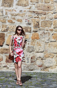 Portrait of young woman standing against brick wall